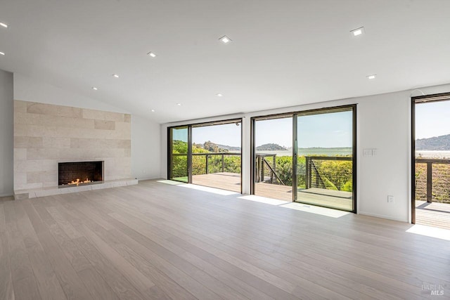 unfurnished living room featuring vaulted ceiling, light wood-style floors, and a large fireplace