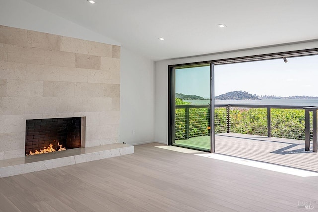 unfurnished living room with wood finished floors, a fireplace, and vaulted ceiling