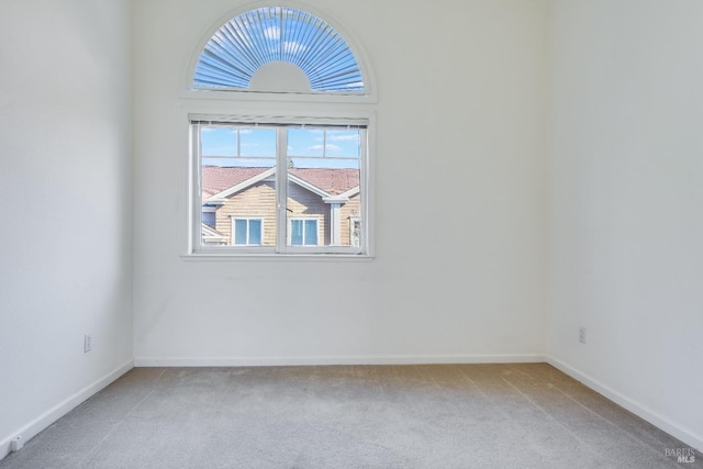 unfurnished room featuring baseboards and light carpet