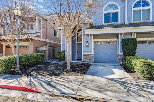 view of front of property with fence, concrete driveway, an attached garage, and stone siding