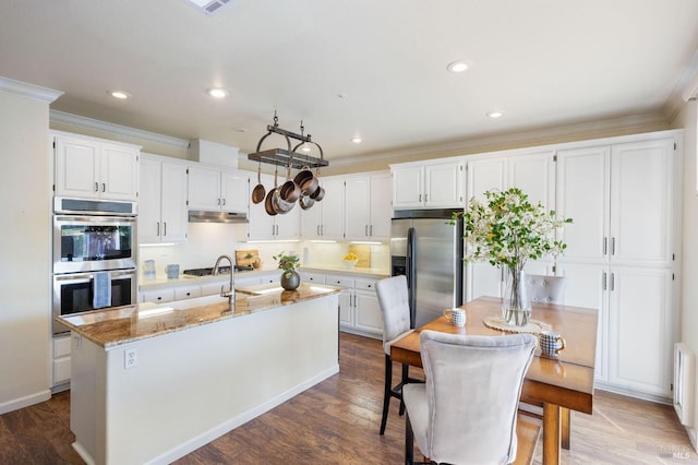 kitchen with under cabinet range hood, a kitchen island with sink, appliances with stainless steel finishes, and white cabinets