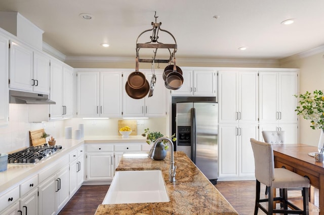 kitchen featuring white cabinetry, under cabinet range hood, appliances with stainless steel finishes, and a sink