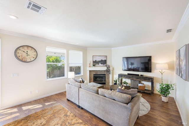 living area with a high end fireplace, visible vents, wood finished floors, and ornamental molding