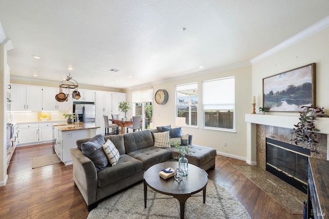 living area featuring visible vents, dark wood-style floors, a high end fireplace, crown molding, and baseboards