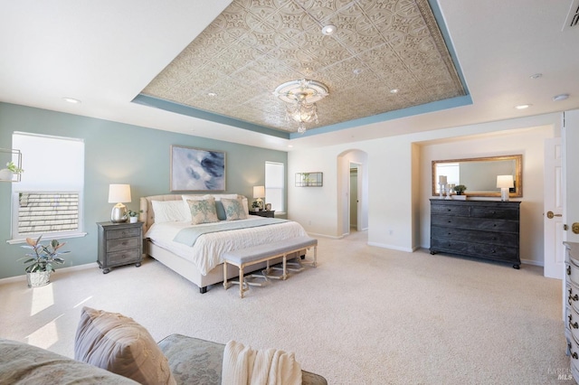 bedroom with baseboards, a raised ceiling, and arched walkways