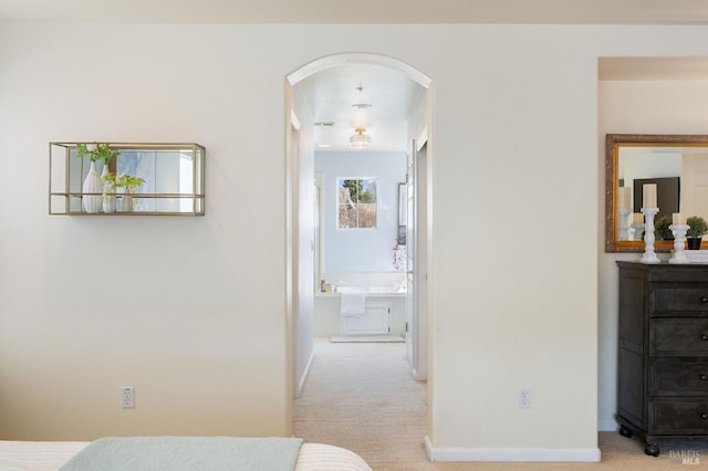 carpeted bedroom with baseboards, arched walkways, and ensuite bath