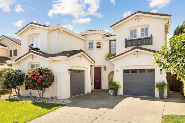 mediterranean / spanish house featuring a garage, concrete driveway, stucco siding, and a tile roof