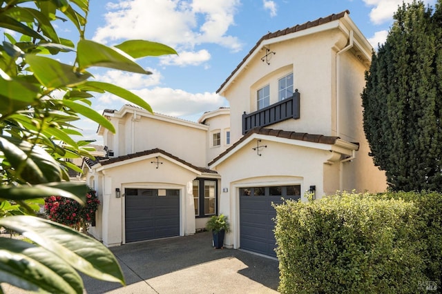 mediterranean / spanish-style house featuring a tiled roof, an attached garage, driveway, and stucco siding