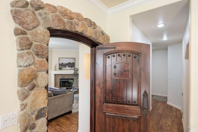 hall featuring baseboards, wood finished floors, and crown molding