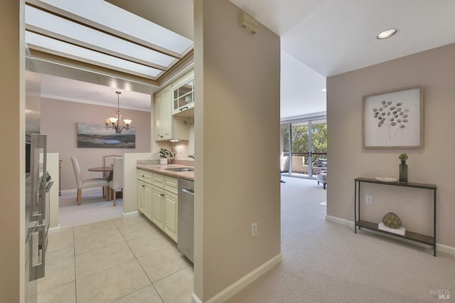 hallway featuring baseboards, light carpet, light tile patterned floors, an inviting chandelier, and a sink