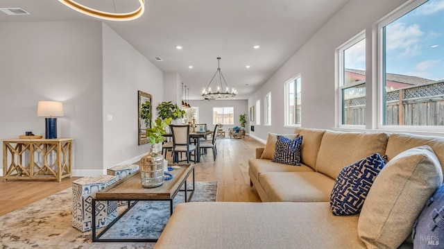 living room featuring visible vents, baseboards, recessed lighting, wood finished floors, and a notable chandelier