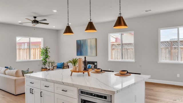 kitchen with light wood finished floors, open floor plan, plenty of natural light, and pendant lighting