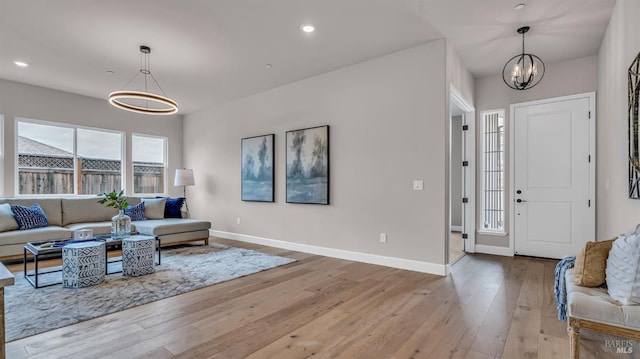 living area featuring recessed lighting, baseboards, an inviting chandelier, and light wood-style flooring