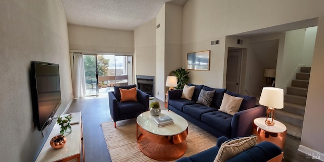 living room with visible vents, a textured ceiling, a towering ceiling, and stairs