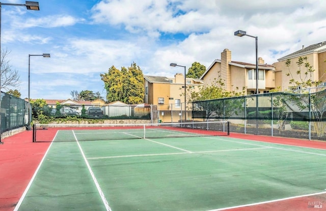 view of tennis court featuring community basketball court and fence