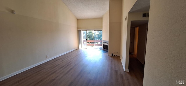 hall with dark wood-style flooring, baseboards, a textured wall, a textured ceiling, and visible vents