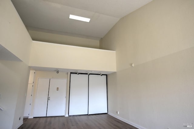 unfurnished bedroom featuring baseboards, dark wood finished floors, and vaulted ceiling