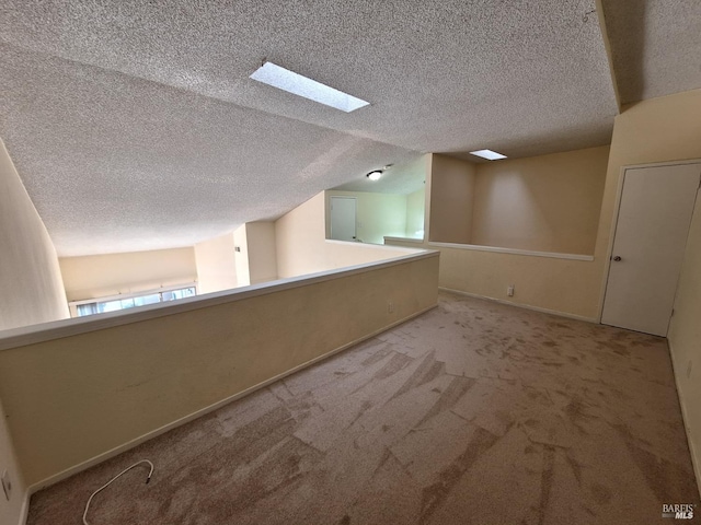 spare room with vaulted ceiling with skylight, baseboards, carpet, and a textured ceiling