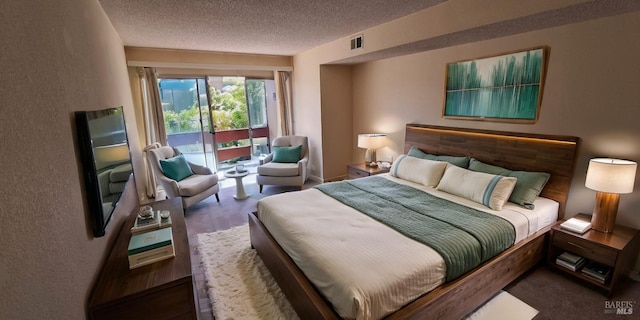 bedroom featuring access to exterior, visible vents, and a textured ceiling