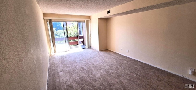 spare room with carpet floors, a textured wall, and a textured ceiling