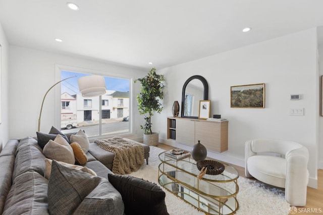 living area with recessed lighting, baseboards, and light wood-style flooring