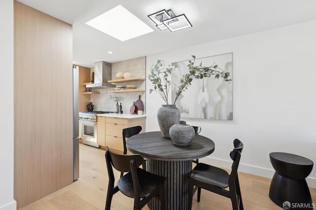 dining space with a skylight, recessed lighting, baseboards, and light wood finished floors