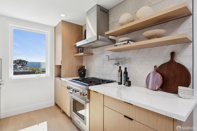 kitchen with light stone counters, open shelves, stainless steel range, exhaust hood, and backsplash