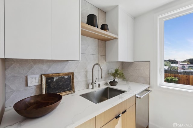 kitchen with a sink, decorative backsplash, light stone countertops, and modern cabinets