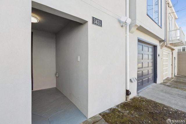 view of exterior entry featuring an attached garage and stucco siding