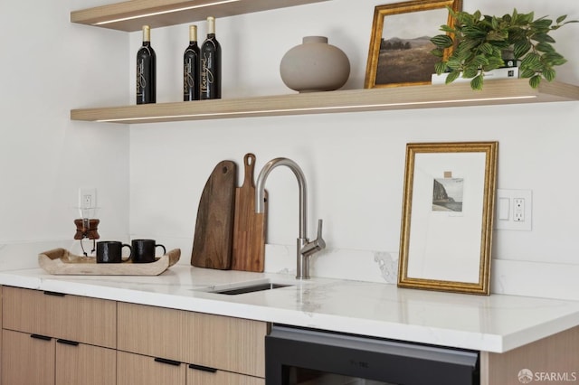 room details featuring light stone counters, dishwashing machine, light brown cabinetry, and a sink