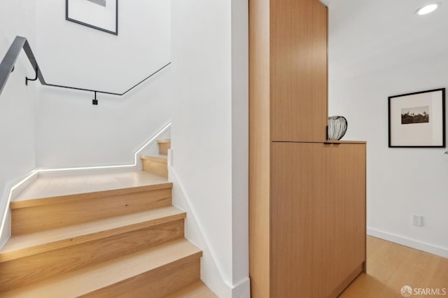 stairway with recessed lighting, wood finished floors, and baseboards