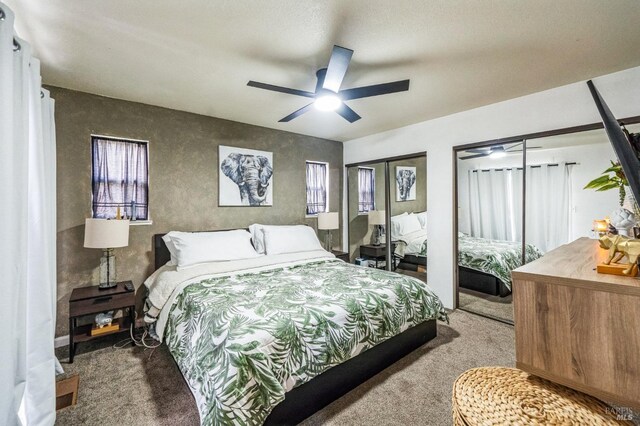 carpeted bedroom with multiple windows, two closets, and ceiling fan