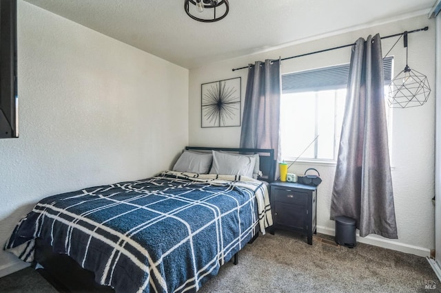 carpeted bedroom featuring a textured wall and baseboards