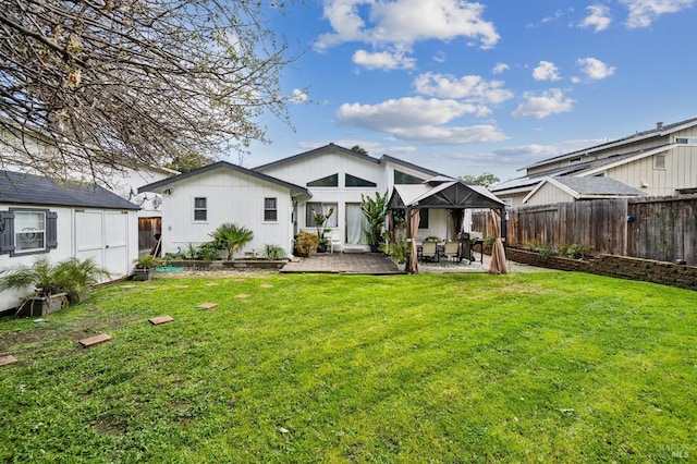 rear view of property featuring an outbuilding, a lawn, a shed, fence, and a patio area