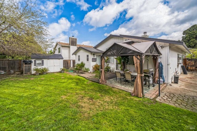 rear view of property with an outbuilding, a fenced backyard, a chimney, a storage shed, and a patio area