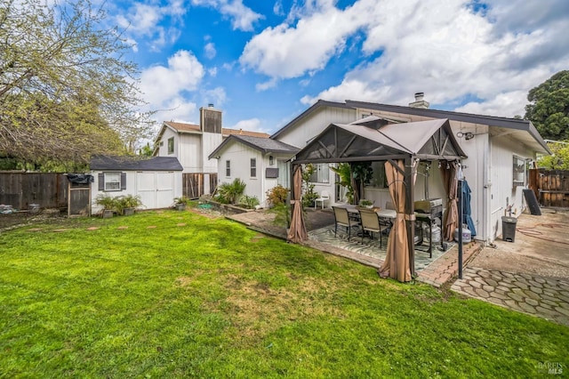 back of house featuring a fenced backyard, a chimney, an outdoor structure, a storage unit, and a patio area