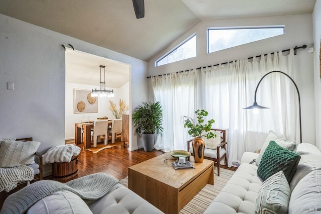 living room with ceiling fan with notable chandelier, wood finished floors, and vaulted ceiling