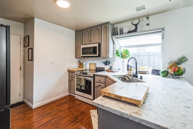 kitchen featuring visible vents, dark wood-type flooring, light countertops, stainless steel appliances, and a sink