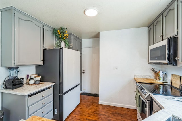 kitchen with gray cabinetry, freestanding refrigerator, stainless steel range with electric cooktop, baseboards, and dark wood-style flooring