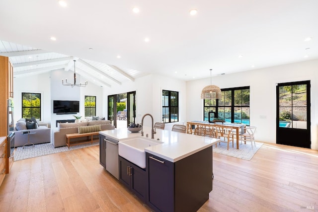 kitchen featuring a sink, light wood-type flooring, a kitchen island with sink, and light countertops