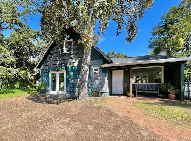 view of front of house with french doors, covered porch, and a chimney