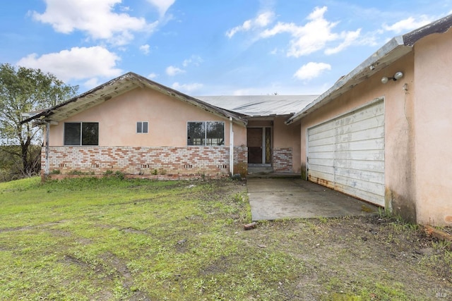 view of front of house featuring brick siding, stucco siding, a front yard, and an attached garage