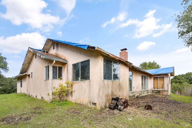 view of property exterior with crawl space, stucco siding, and a chimney