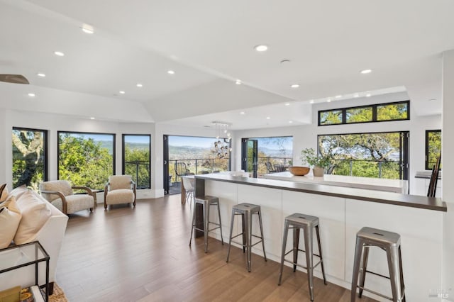 kitchen with recessed lighting, a kitchen bar, open floor plan, and light wood finished floors