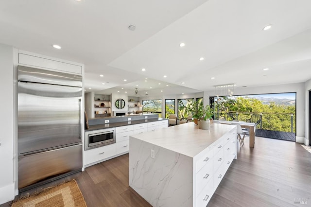 kitchen featuring dark wood finished floors, built in appliances, white cabinetry, and modern cabinets