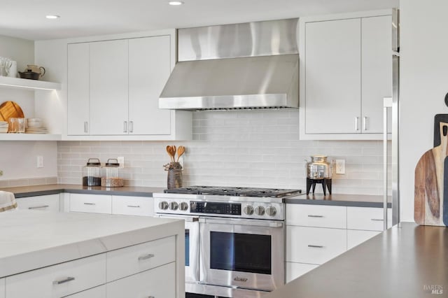 kitchen with high end stainless steel range oven, open shelves, wall chimney exhaust hood, and white cabinetry