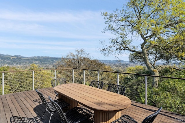 wooden terrace with outdoor dining space and a mountain view