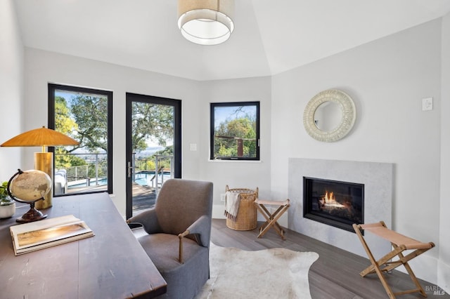 office with a glass covered fireplace, lofted ceiling, and wood finished floors