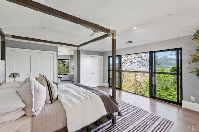 bedroom featuring visible vents, multiple closets, and wood finished floors