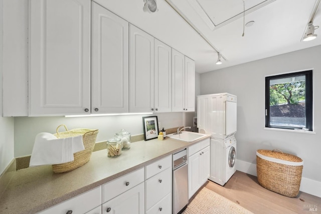 washroom featuring light wood-style flooring, a sink, cabinet space, stacked washer / dryer, and attic access